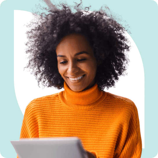 A woman with curly hair is smiling while using a tablet.