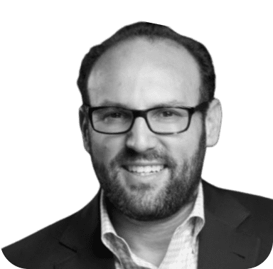 A black and white photo of a man wearing glasses and a suit.