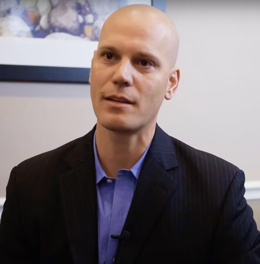A bald man in a suit sitting in an office.